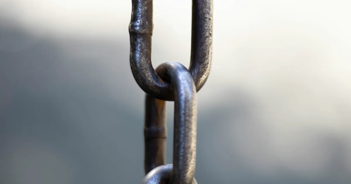 Primer plano de una cadena metálica con el cielo de fondo